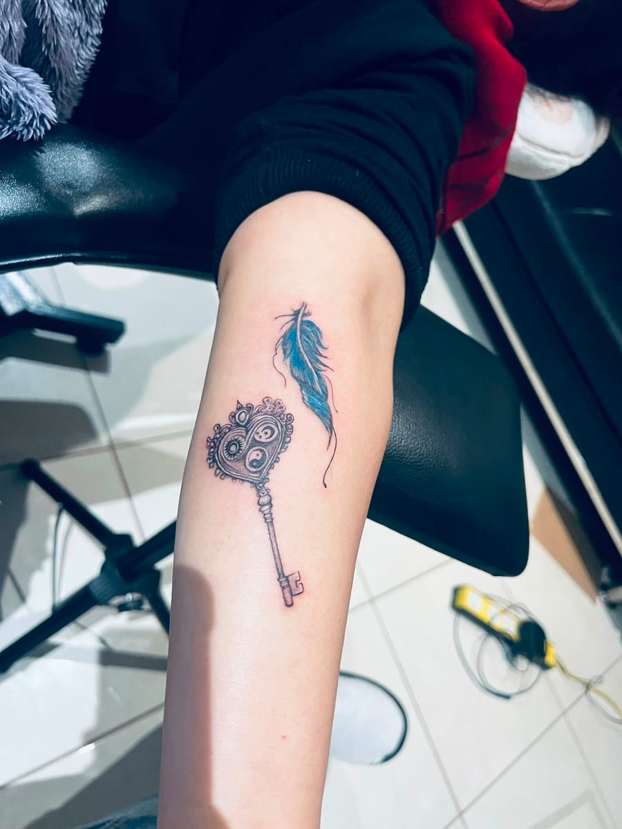 Black and grey realism key and feather tattoo